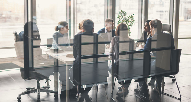 A board of people meeting behind glass walls.