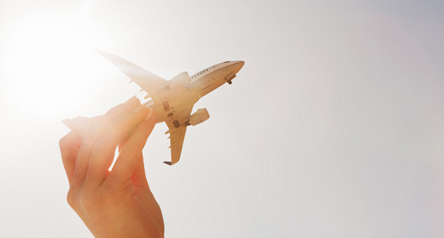 A hand holding a toy airplane against the sunny sky.