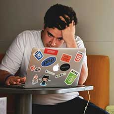 Thoughtful person sitting at desk and looking at computer screen