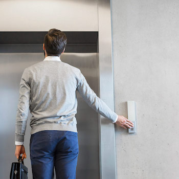 Business man presses for an elevator