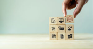 Wooden blocks in a three-by-three stack. Each block has a different icon on it - suggesting different settings (a shopping cart, a store front, a letter, etc). A hand puts the top right block (reading 'omni') into place.